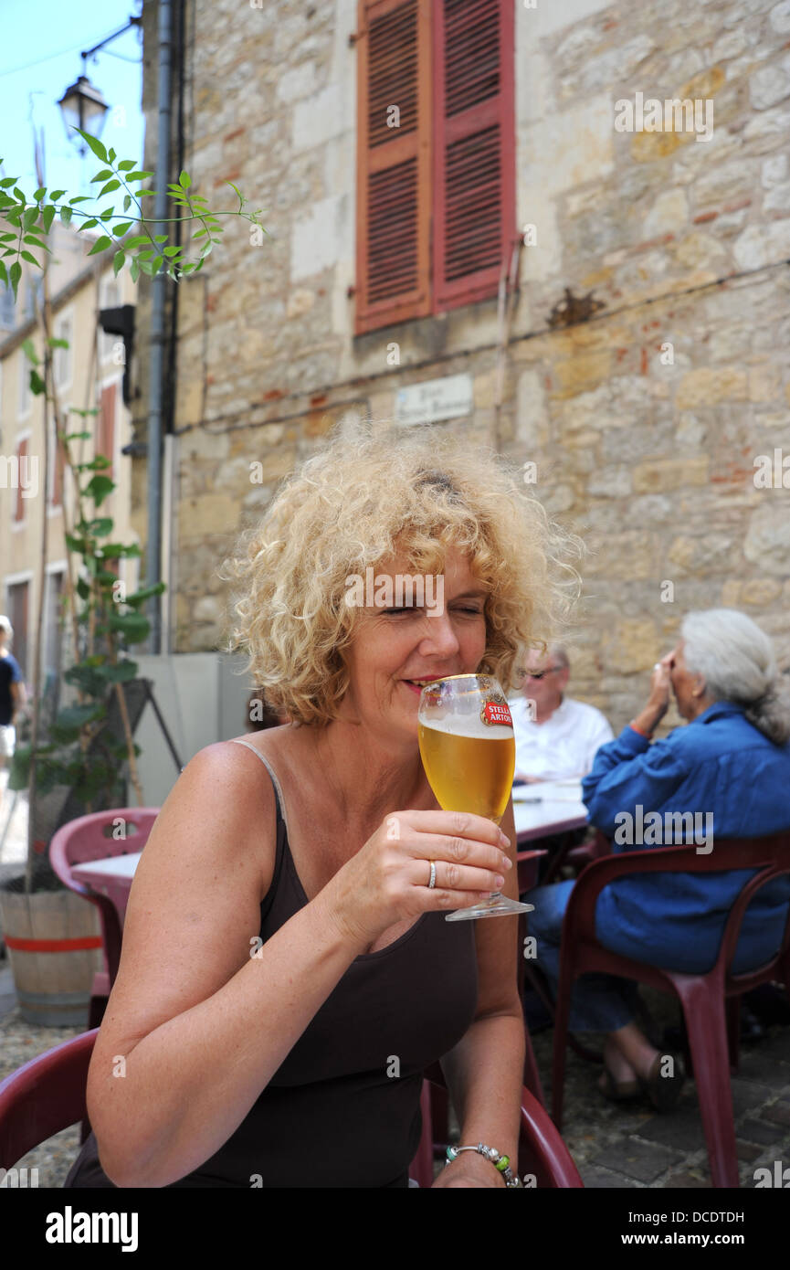 Woman drinking a glass of Stella Artois beer lager outside a bar at Puy L'Eveque in the Lot Region or Department France Stock Photo
