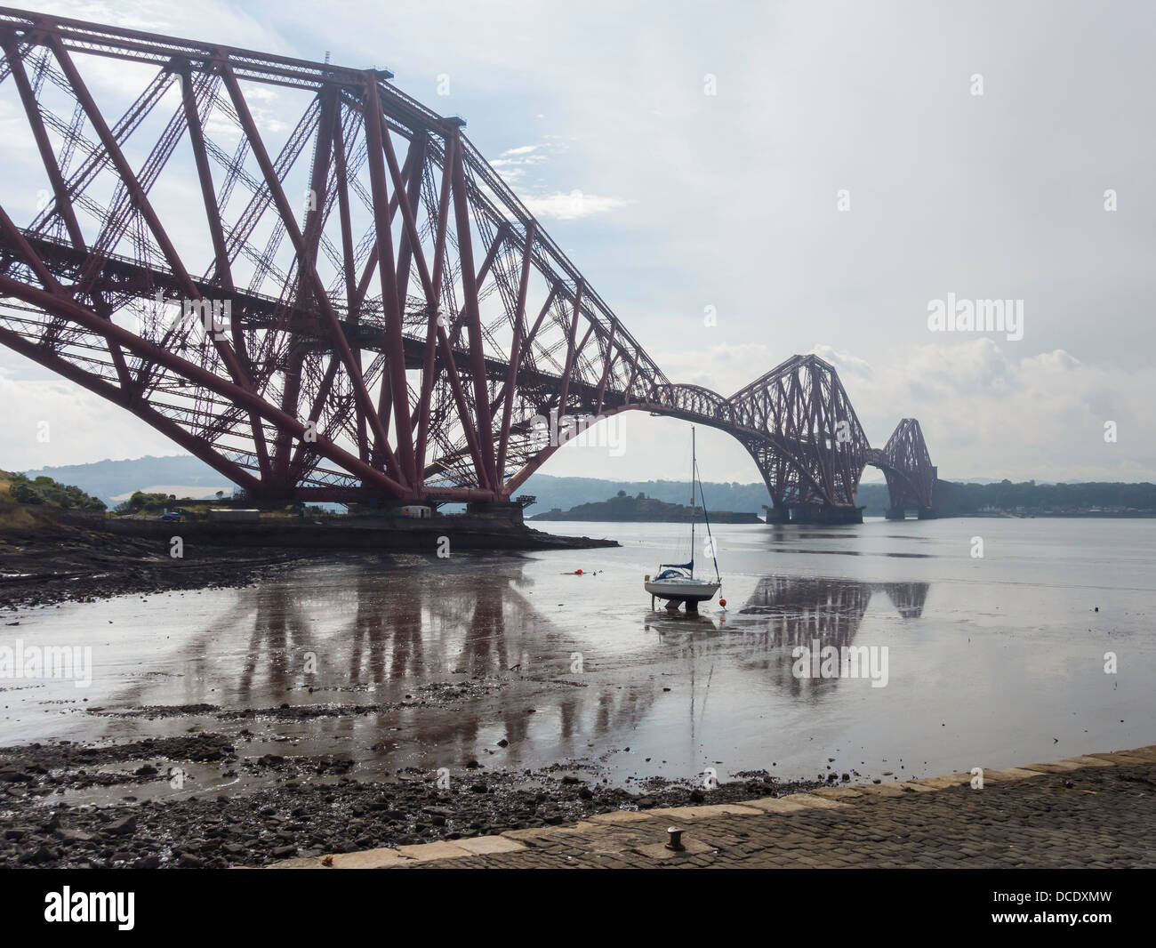 Forth Railway bridge from North Queensferry with boat on mud flats and reflection Stock Photo