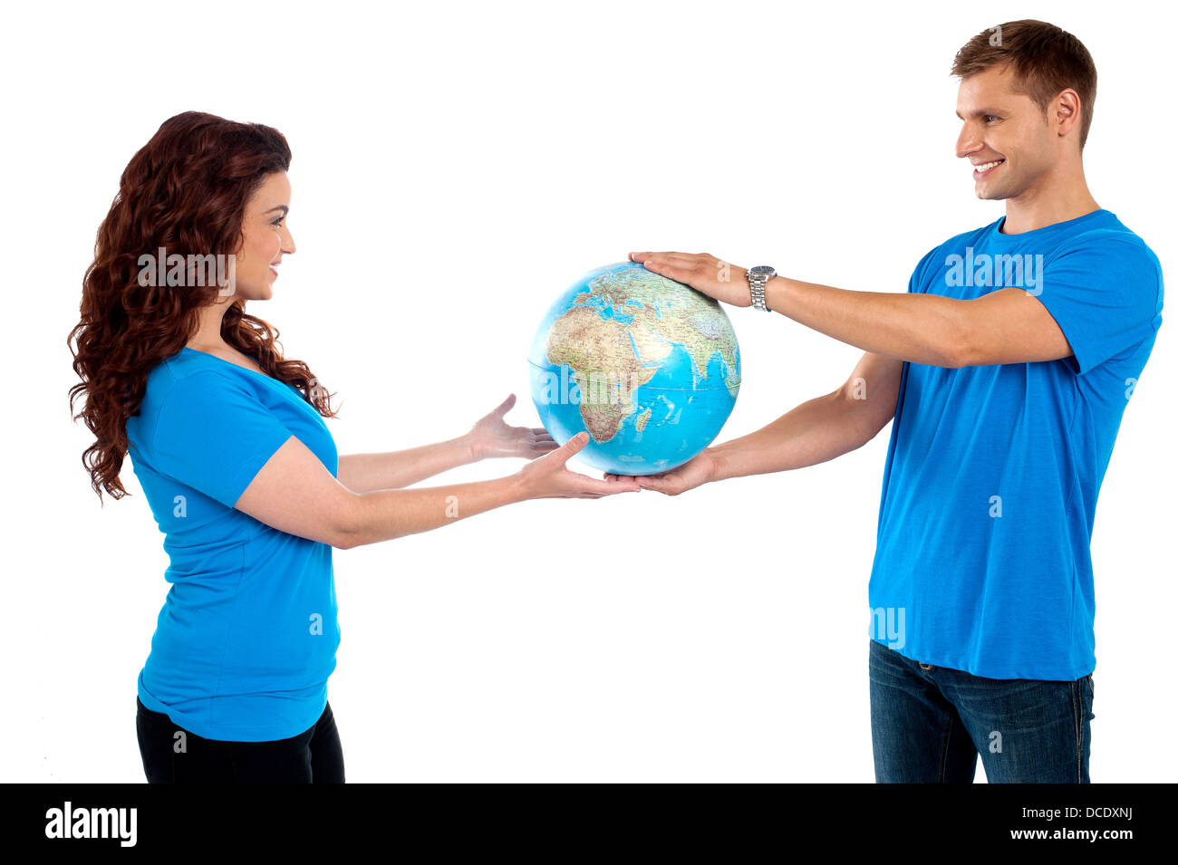 Causal young couple holding globe together and looking at each other Stock Photo