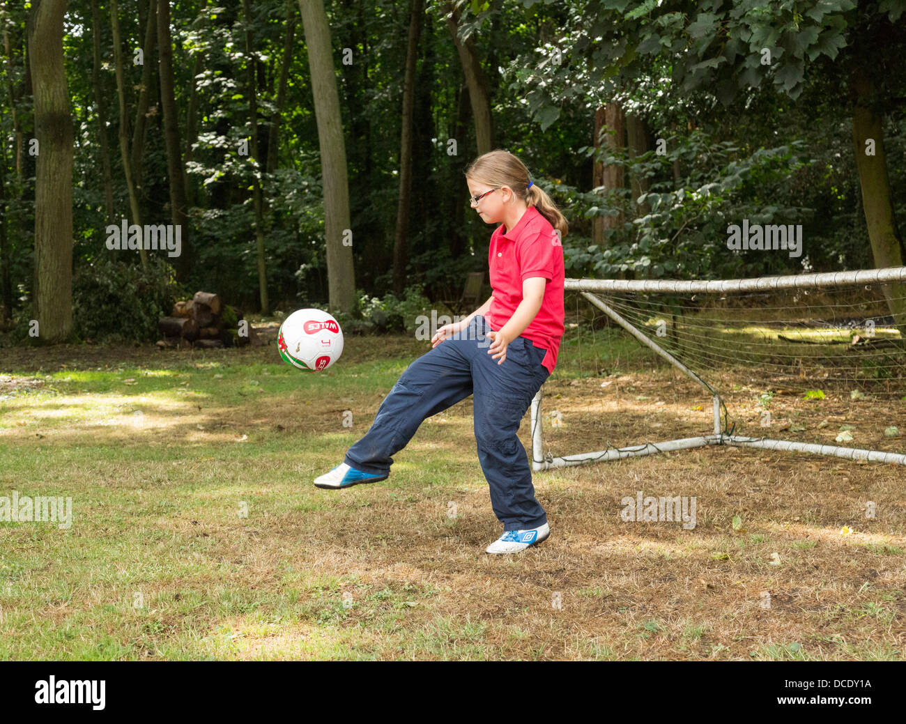 young girl kicking a soccer ball around in back yard Stock Photo