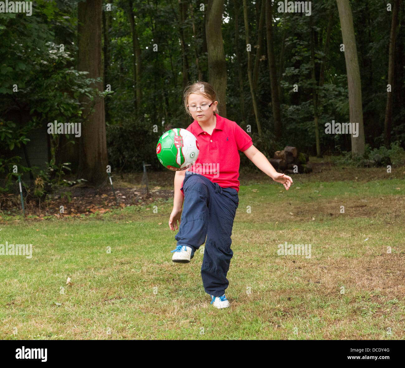young girl kicking a soccer ball around in back yard Stock Photo
