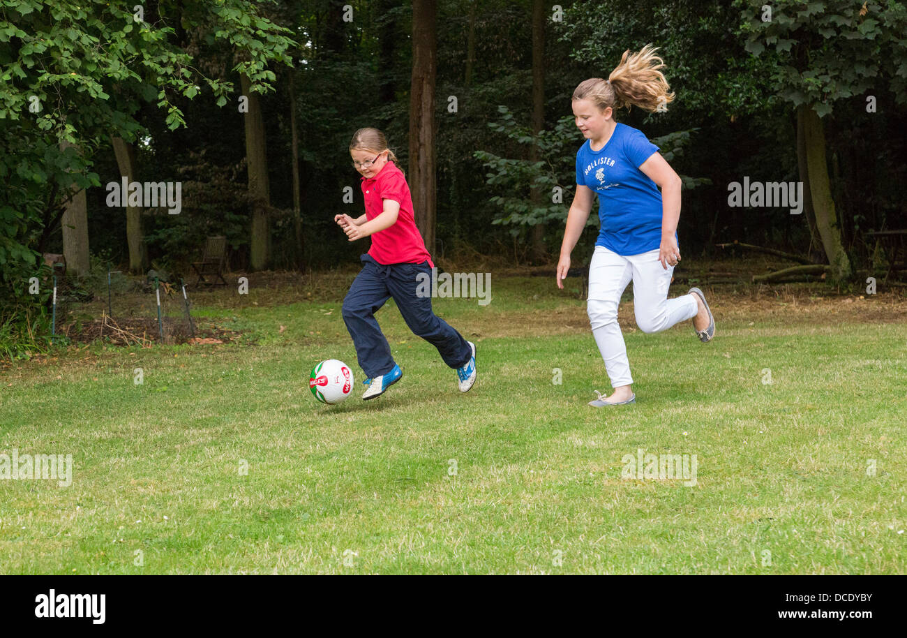 two young girls playing soccer in backyard/garden Stock Photo