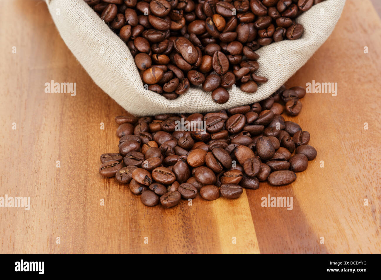 roasted coffee beans spill out of the bag, wooden table Stock Photo