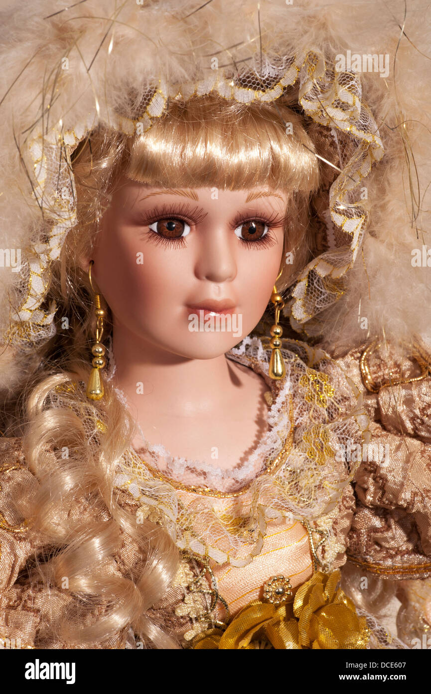 Face of pretty doll with yellow dress, brown eye and blond curly hair Stock Photo