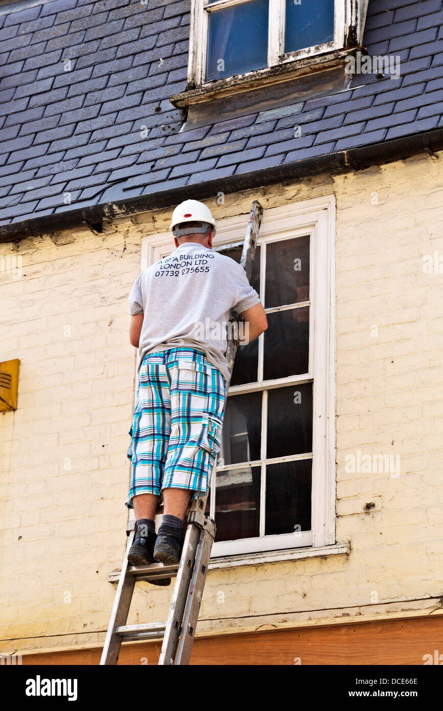 Builder climbing ladder to reach the gutters of a house in St Ives,  Cambridgeshire, England Stock Photo - Alamy