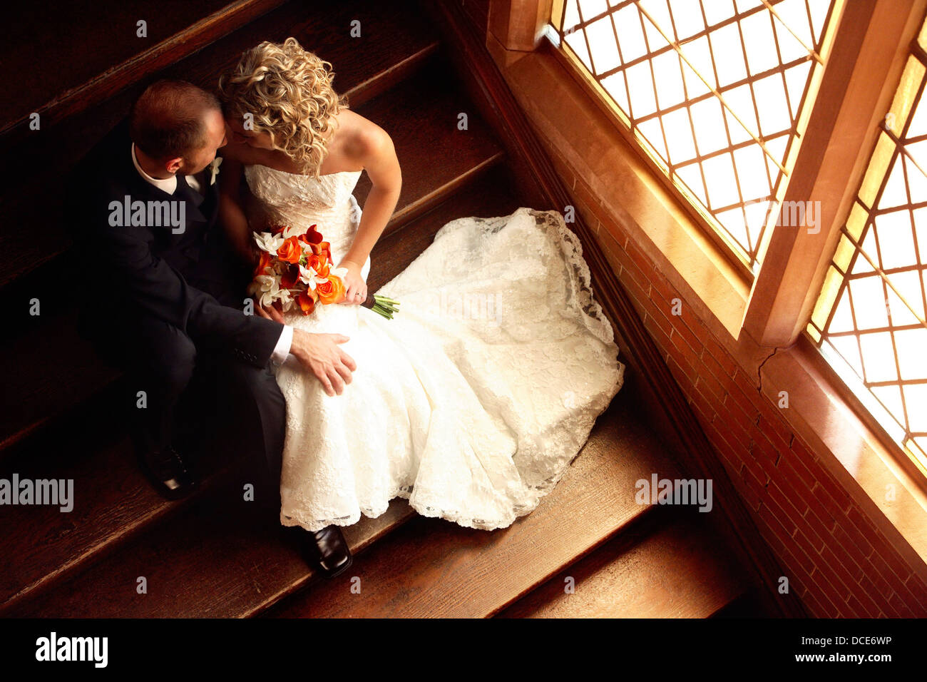 Newlyweds Sitting In Stairway Of Church Stock Photo