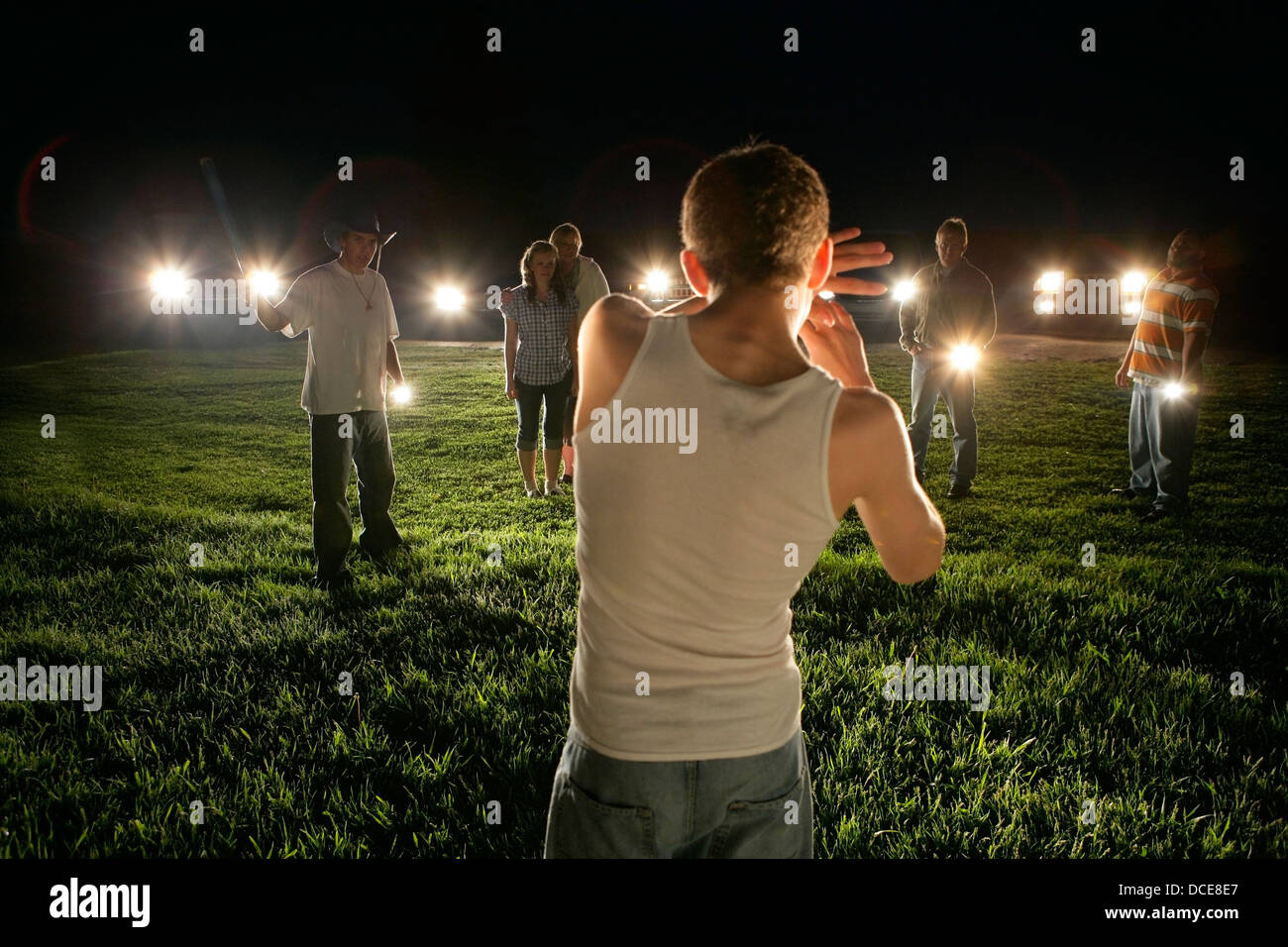 Young Man Outdoors At Night Surrounded By People With Flashlights Stock