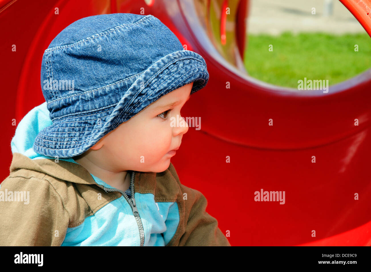 A small baby boy watching other children at play Stock Photo