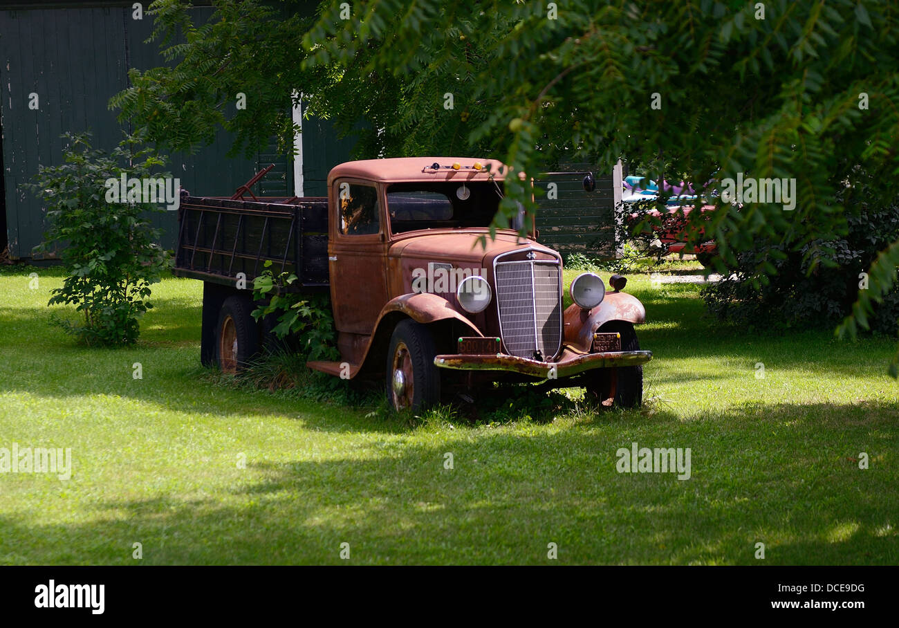 1934 International truck sits abandoned by a barn. Stock Photo
