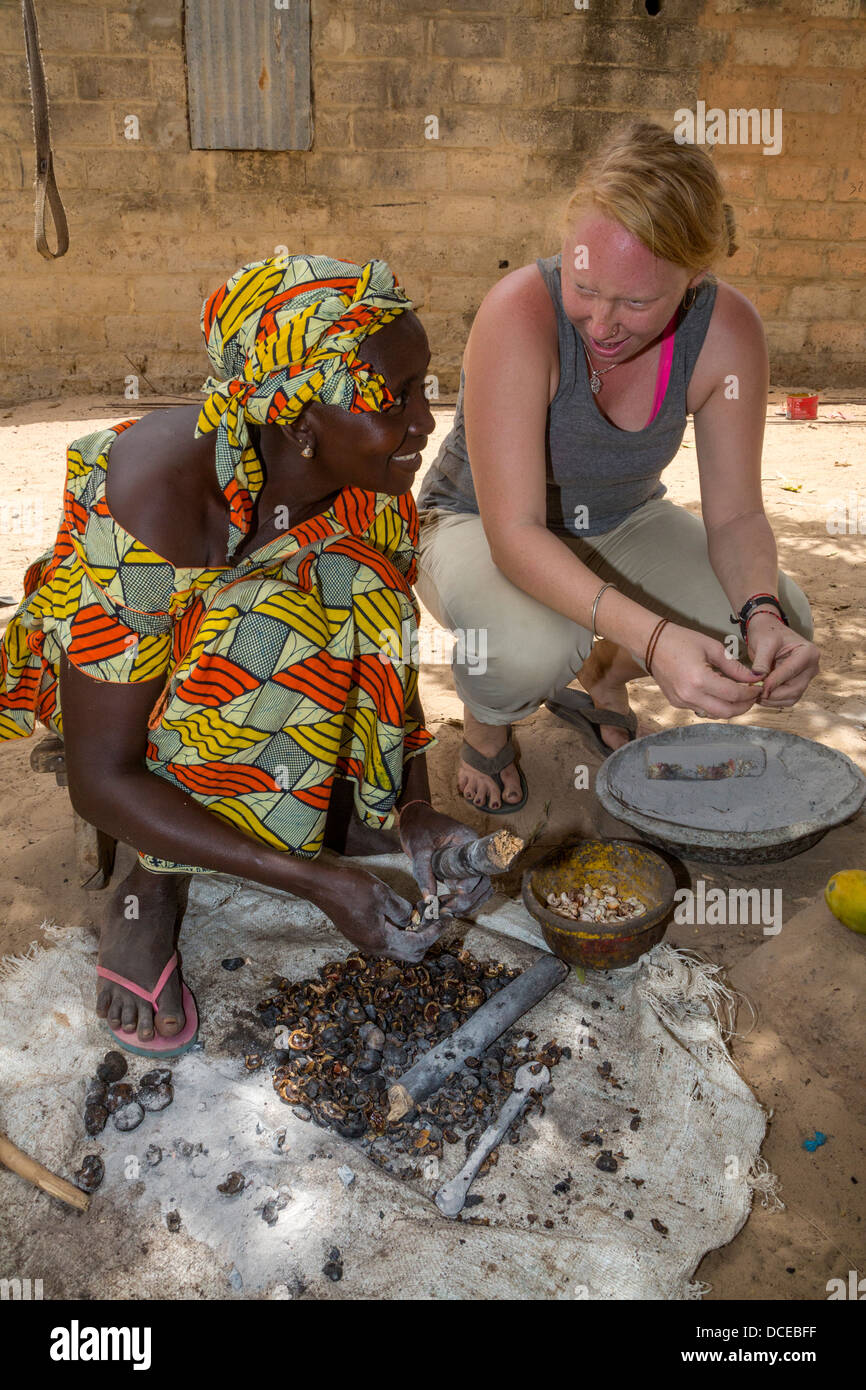 Peace Corps Volunteer Working with Village Woman Removing Hulls from Cashew Nuts.  Serer Ethnic Group. Stock Photo