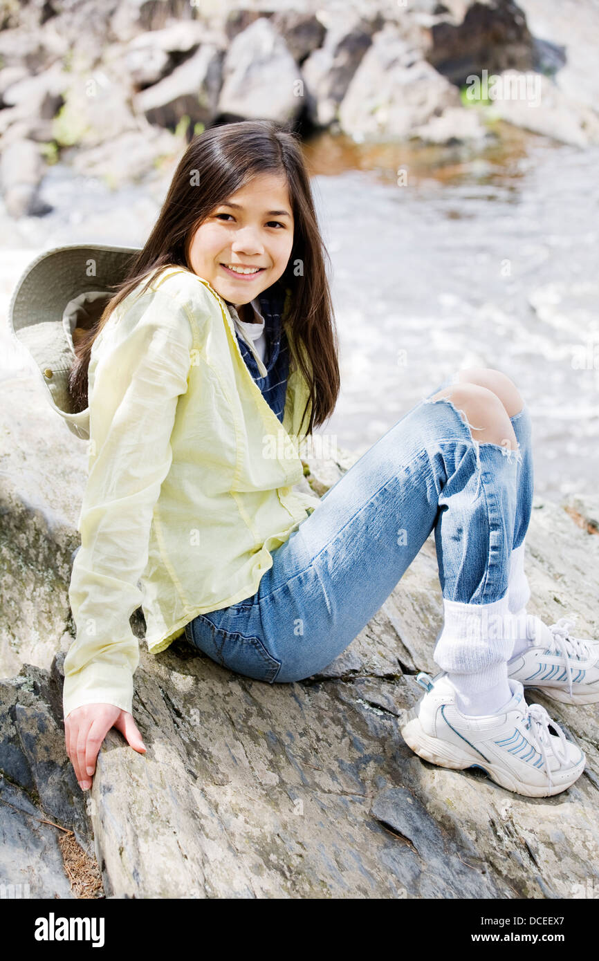 Girl sitting on rock cliff edge Stock Photo - Alamy