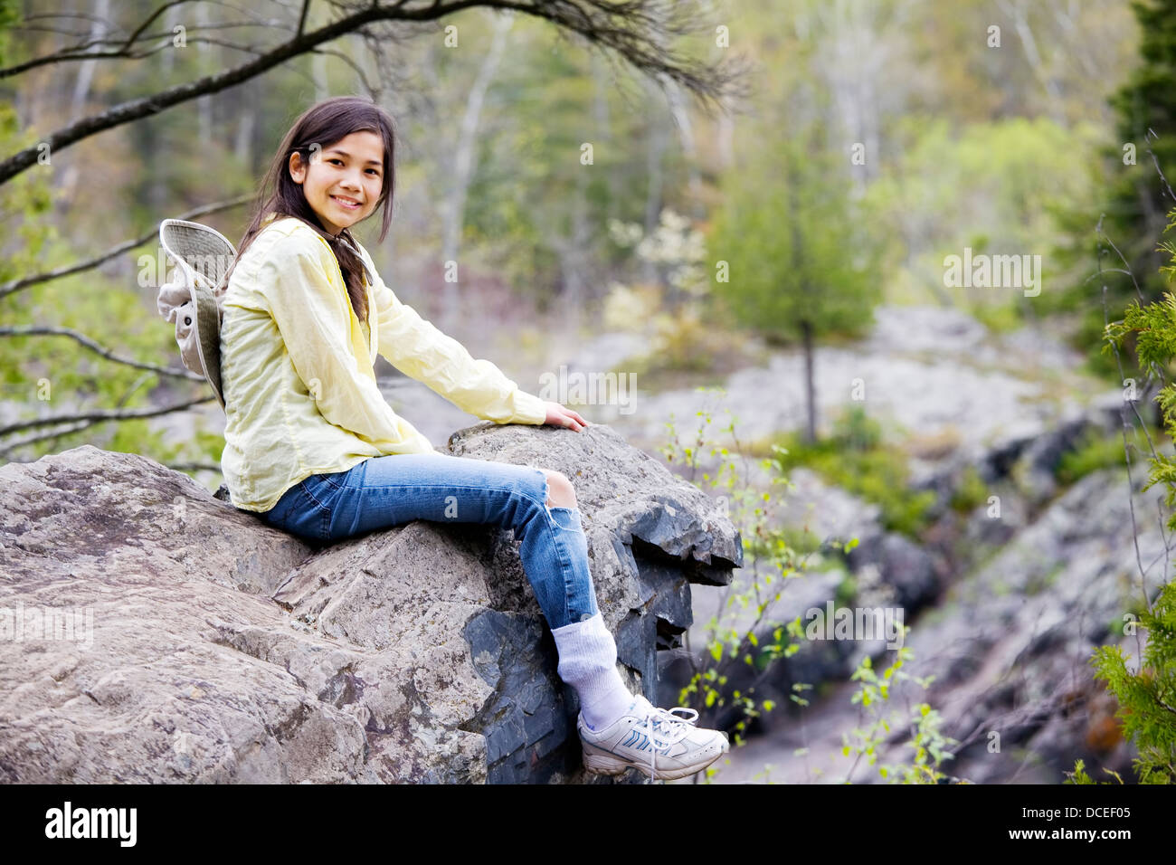Girl sitting on rock cliff edge Stock Photo - Alamy