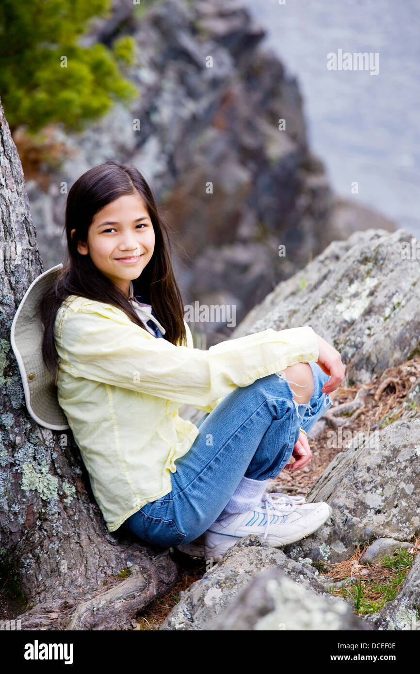 Girl sitting on rock cliff edge Stock Photo - Alamy