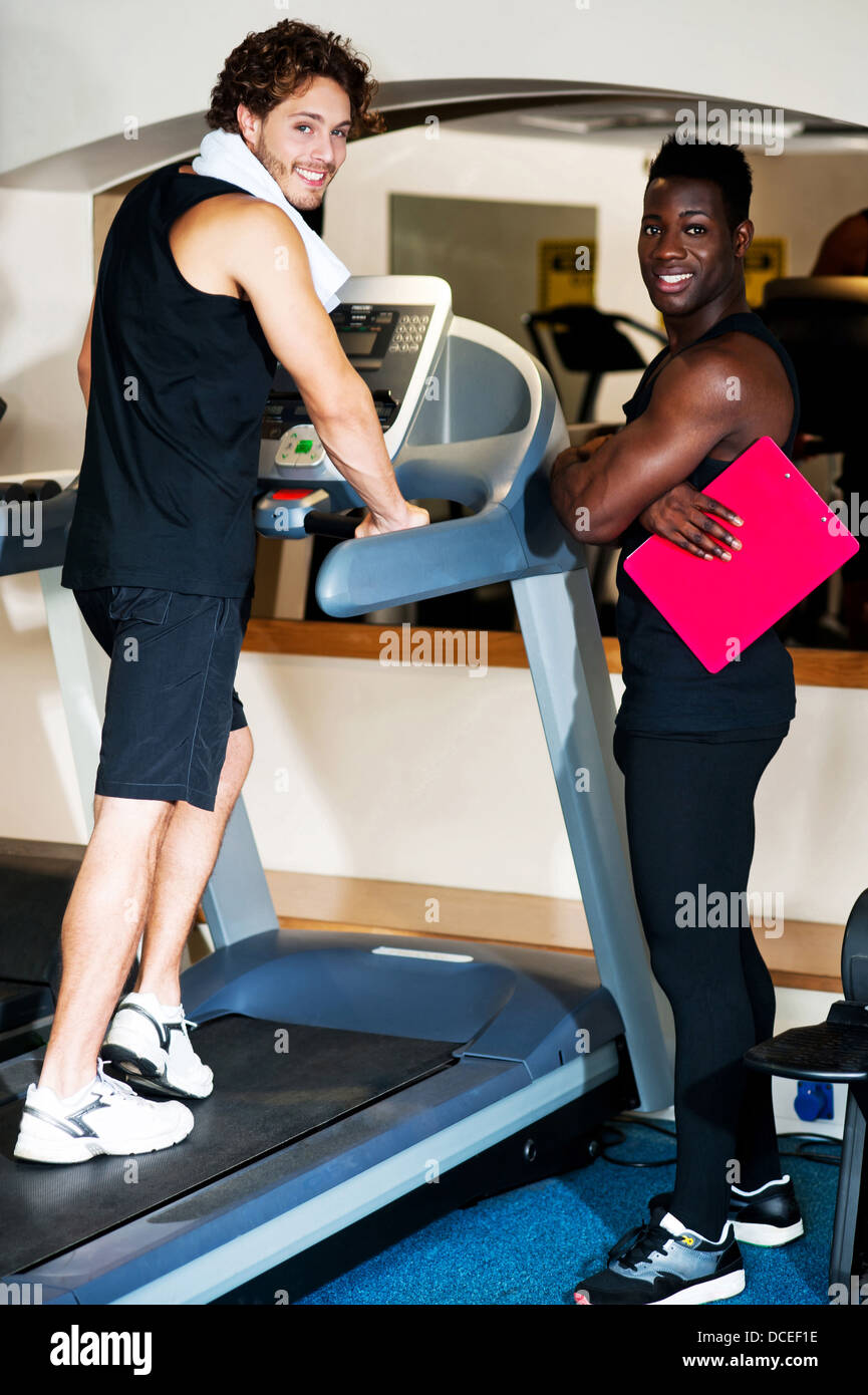 Young african male trainer dedicated to his client. Man doing brisk walking on treadmill Stock Photo Alamy