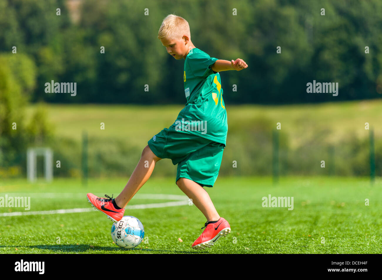 Young football player make exercises on football field, sunny day Stock