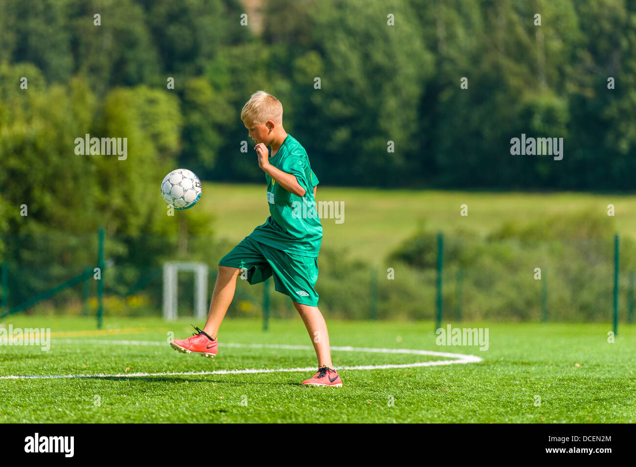 Young football player make exercises on football field, sunny day Stock Photo