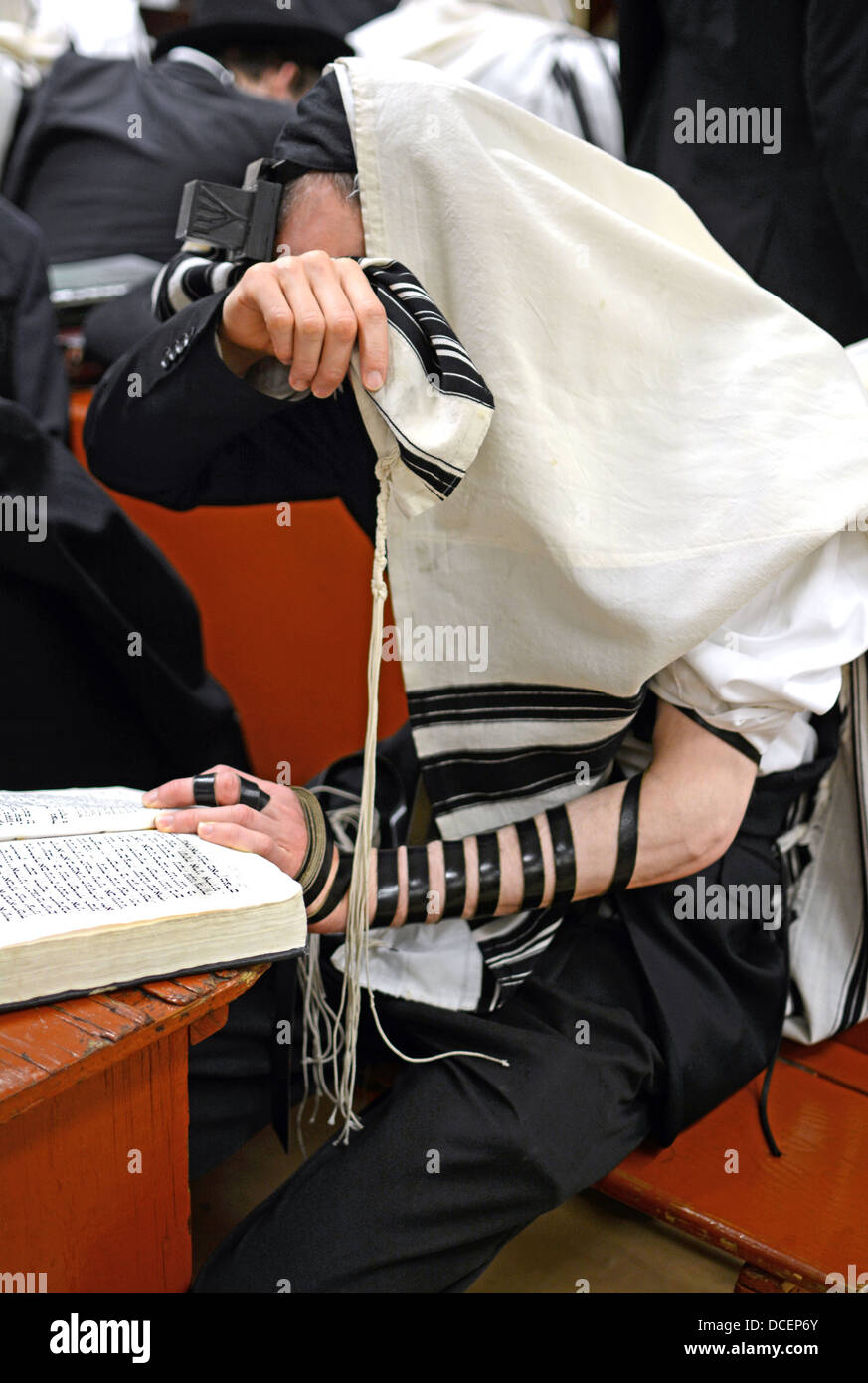 Orthodox Jewish man with tefillin and tallit, sitting alone and