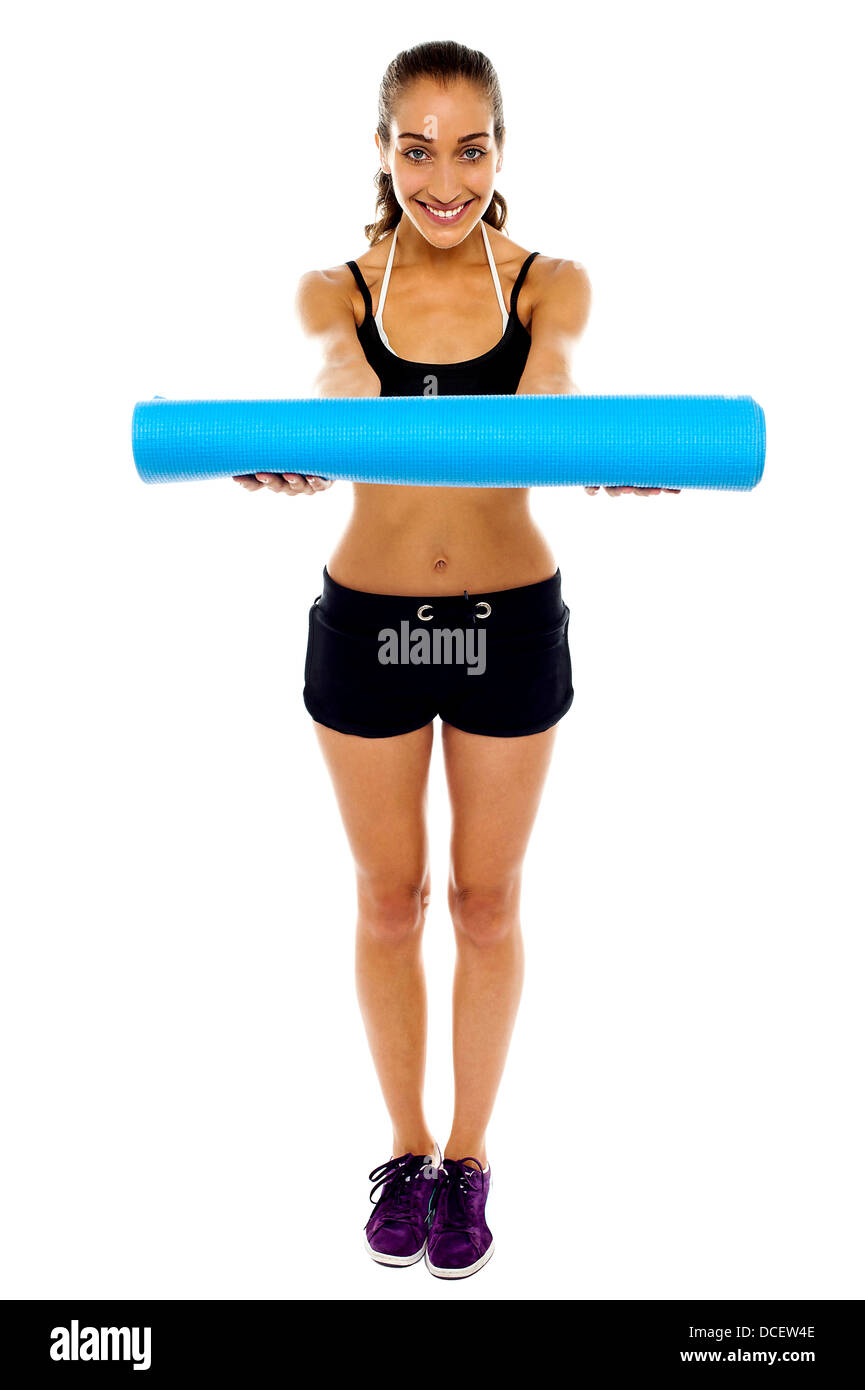 Attractive woman in gym attire holding a blue mat in her outstretched arms Stock Photo