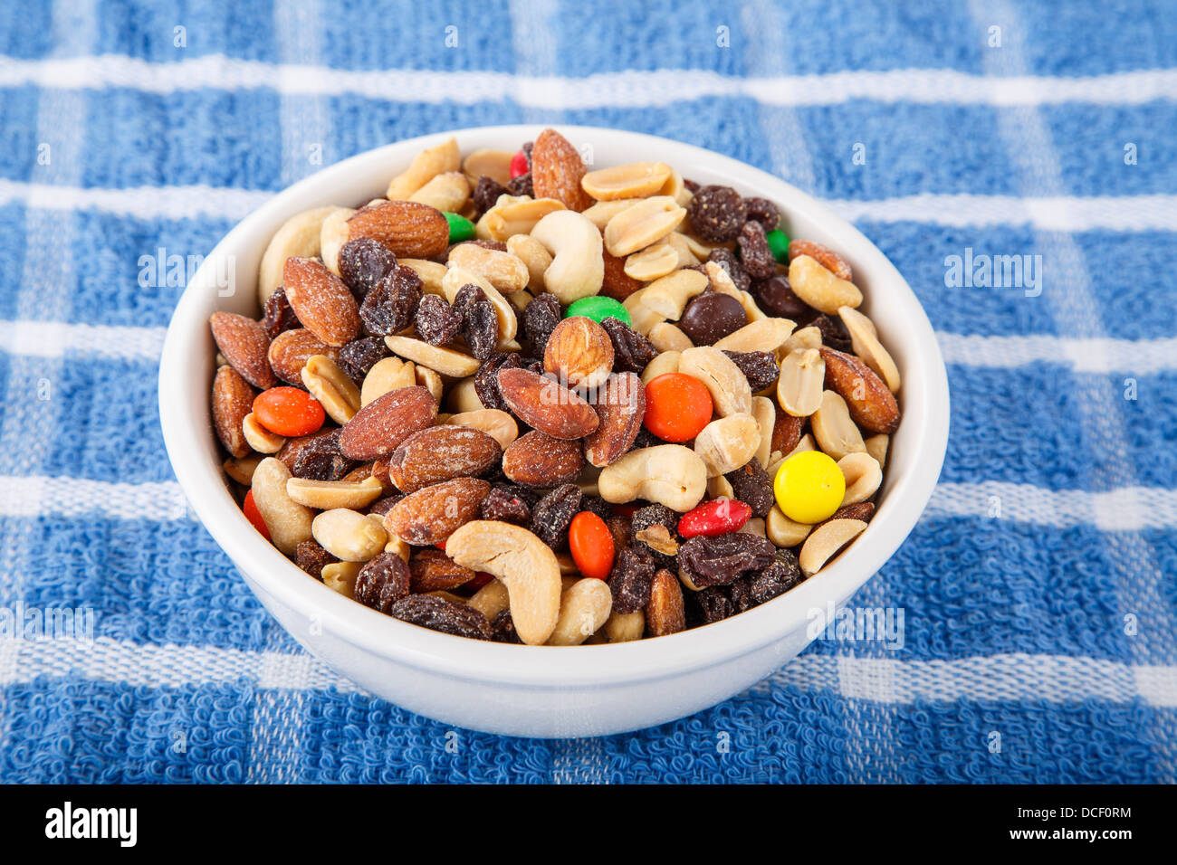 A bowl of trail mix with cashews, almonds, peanuts, raisins, and candy