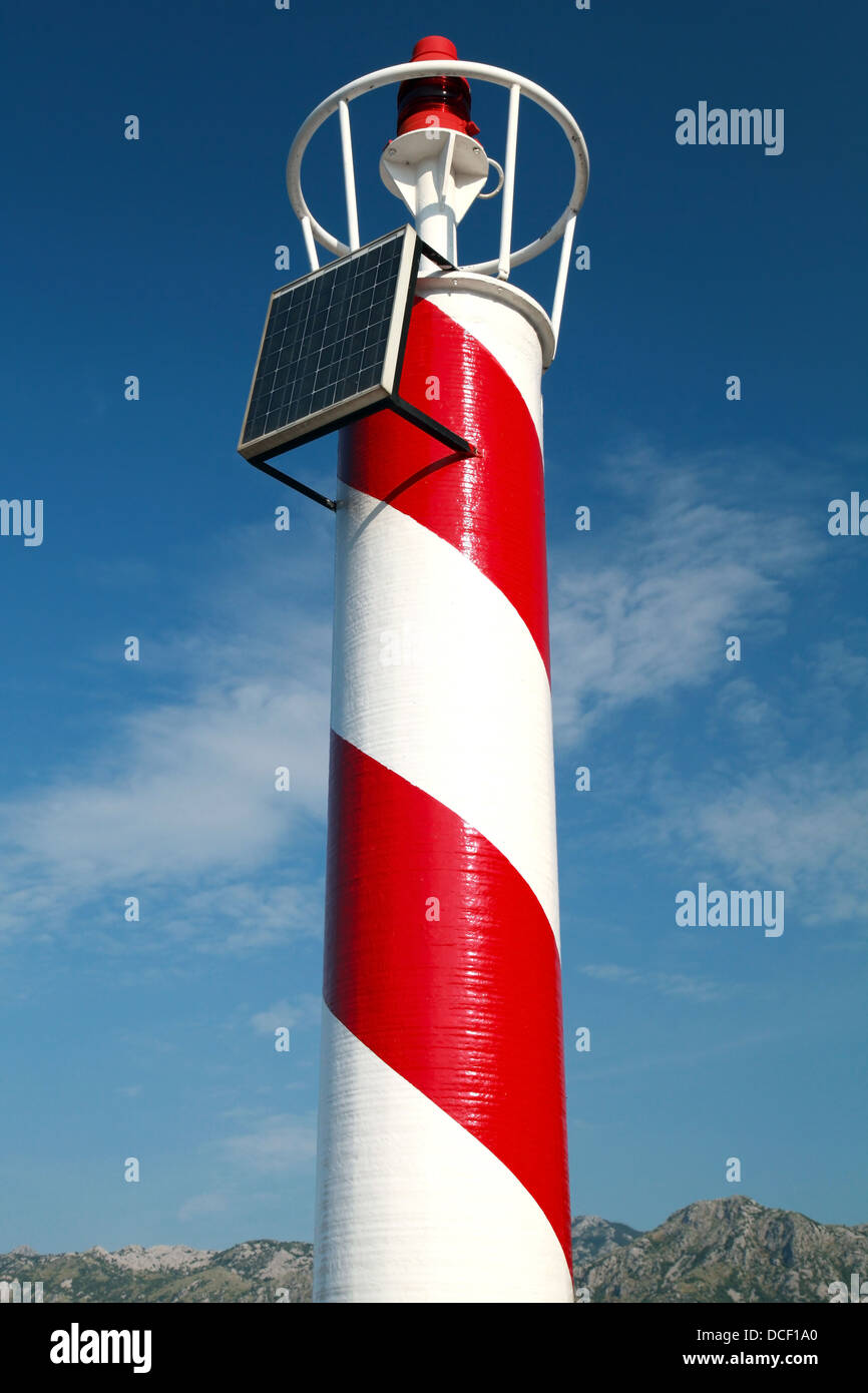 Red and white striped lighthouse above cloudy sky. Perast town, Montenegro Stock Photo