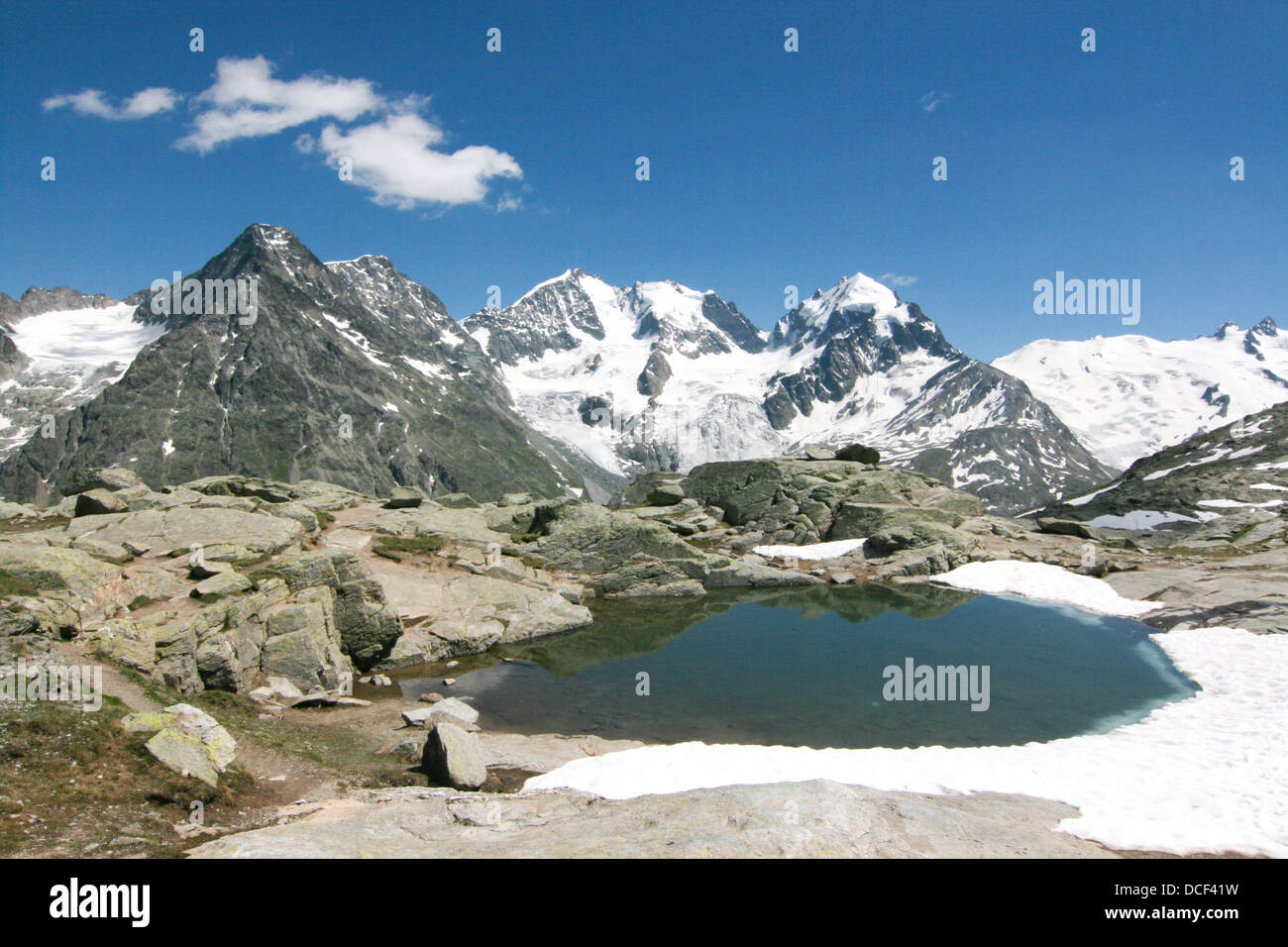 view of the Bernina mountain range across the alpine pond at Fuorcla Surlej Stock Photo