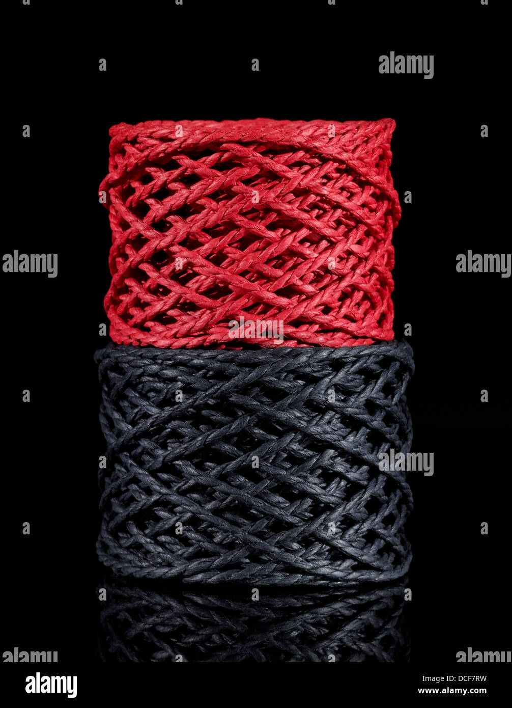 a red and a dark grey string coil in black reflective back Stock Photo ...