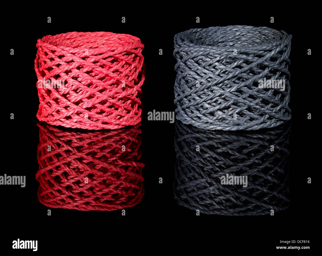 a red and a dark grey string coil in black reflective back Stock Photo ...