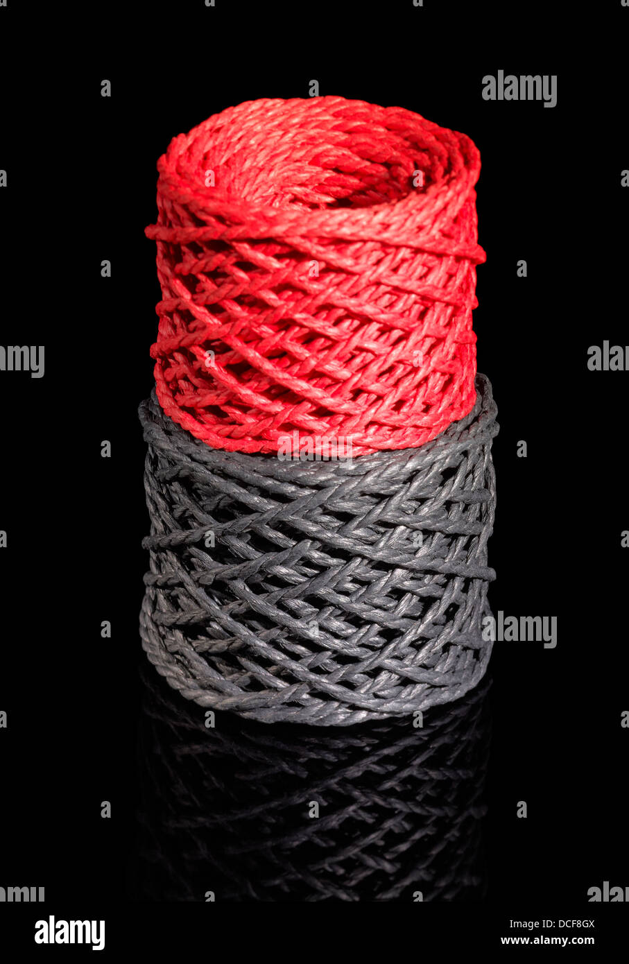 a red and a dark grey string coil in black reflective back Stock Photo ...