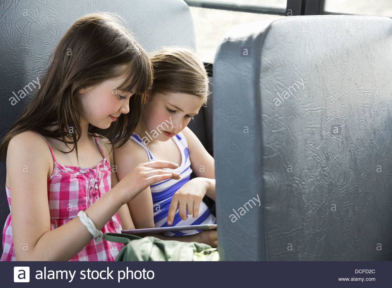Little girls using digital tablet in school bus Stock Photo