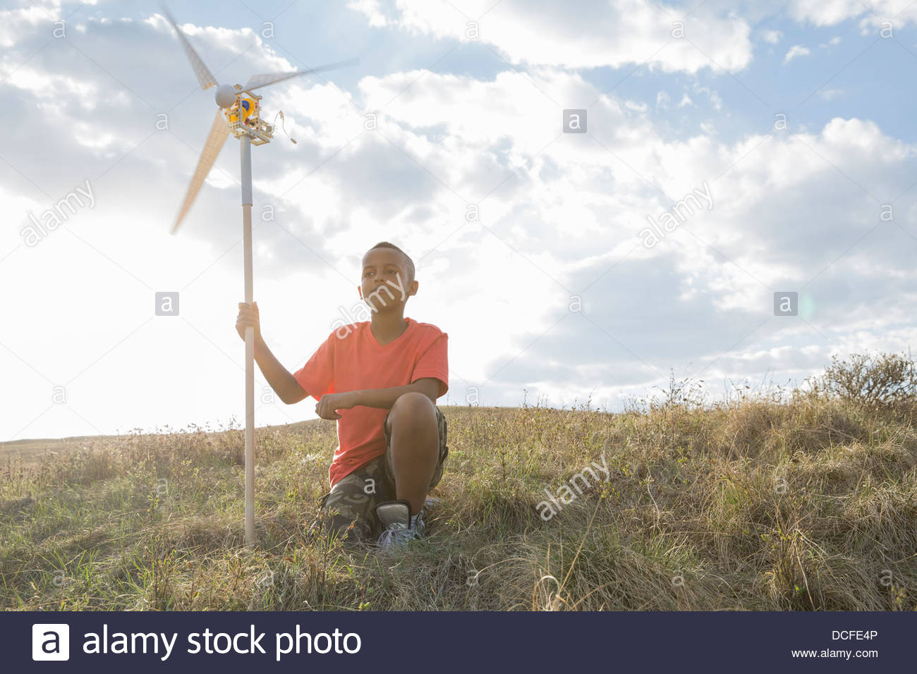 Schoolboy holding wind turbine on hillside Stock Photo