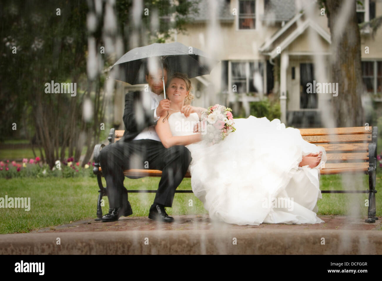 Bride And Groom Sitting On A Park Bench In The Rain Stock Photo - Alamy