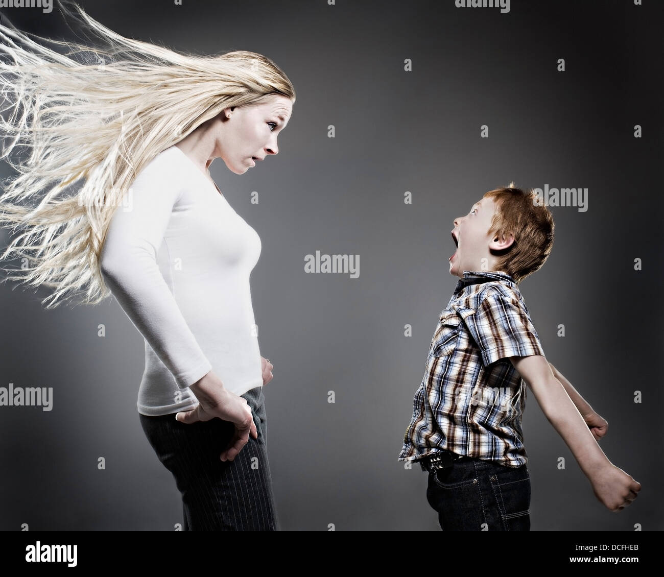 Boy Yelling At His Mother As Her Hair Blows Wildly Stock Photo