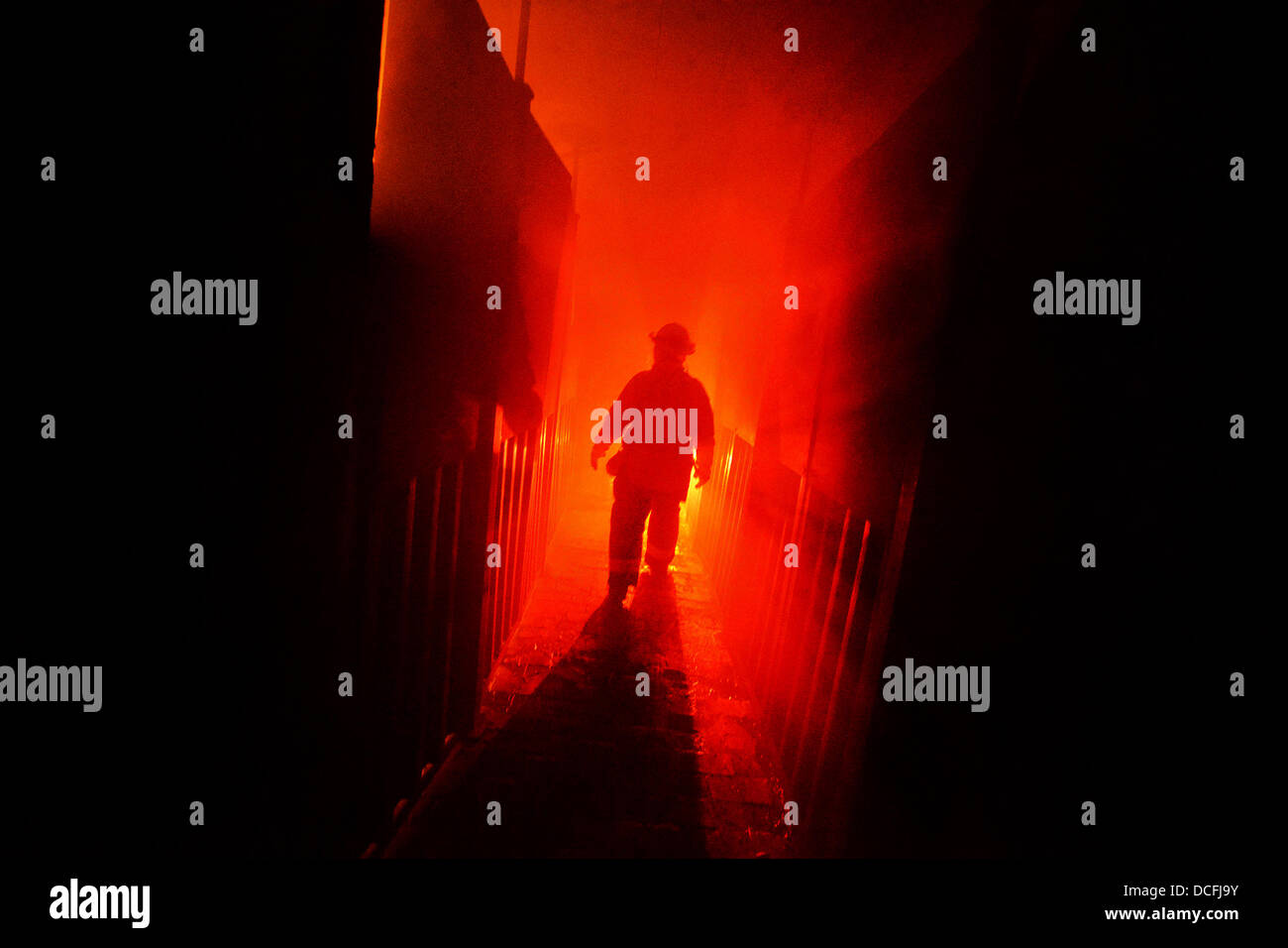 A New York Air National Guard firefighter ducks under flames in a burning building during training at the Suffolk County Fire Academy August 16, 2013 in Yaphank, NY Stock Photo