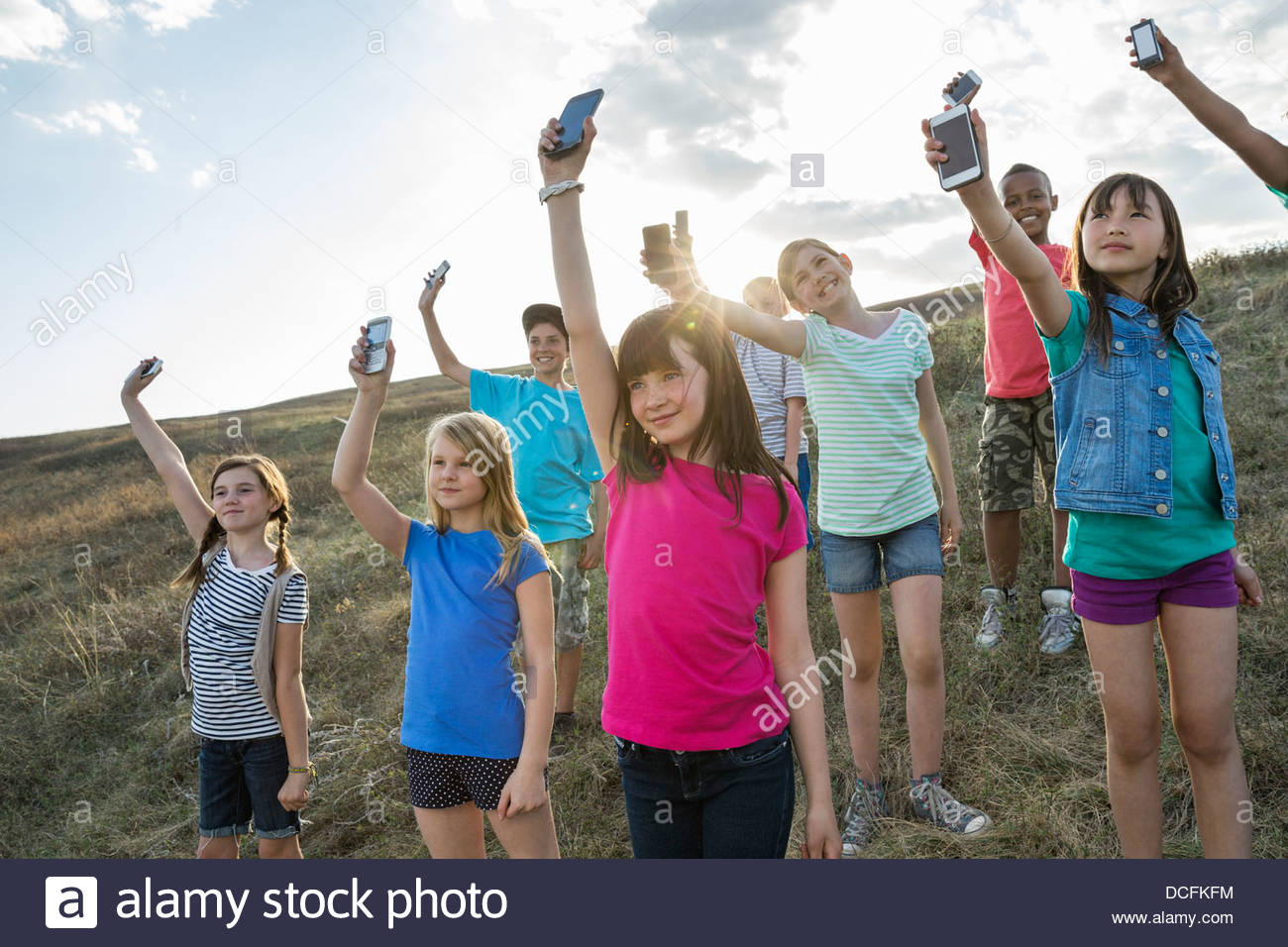 Group of kids holding mobile phones up in the air Stock Photo
