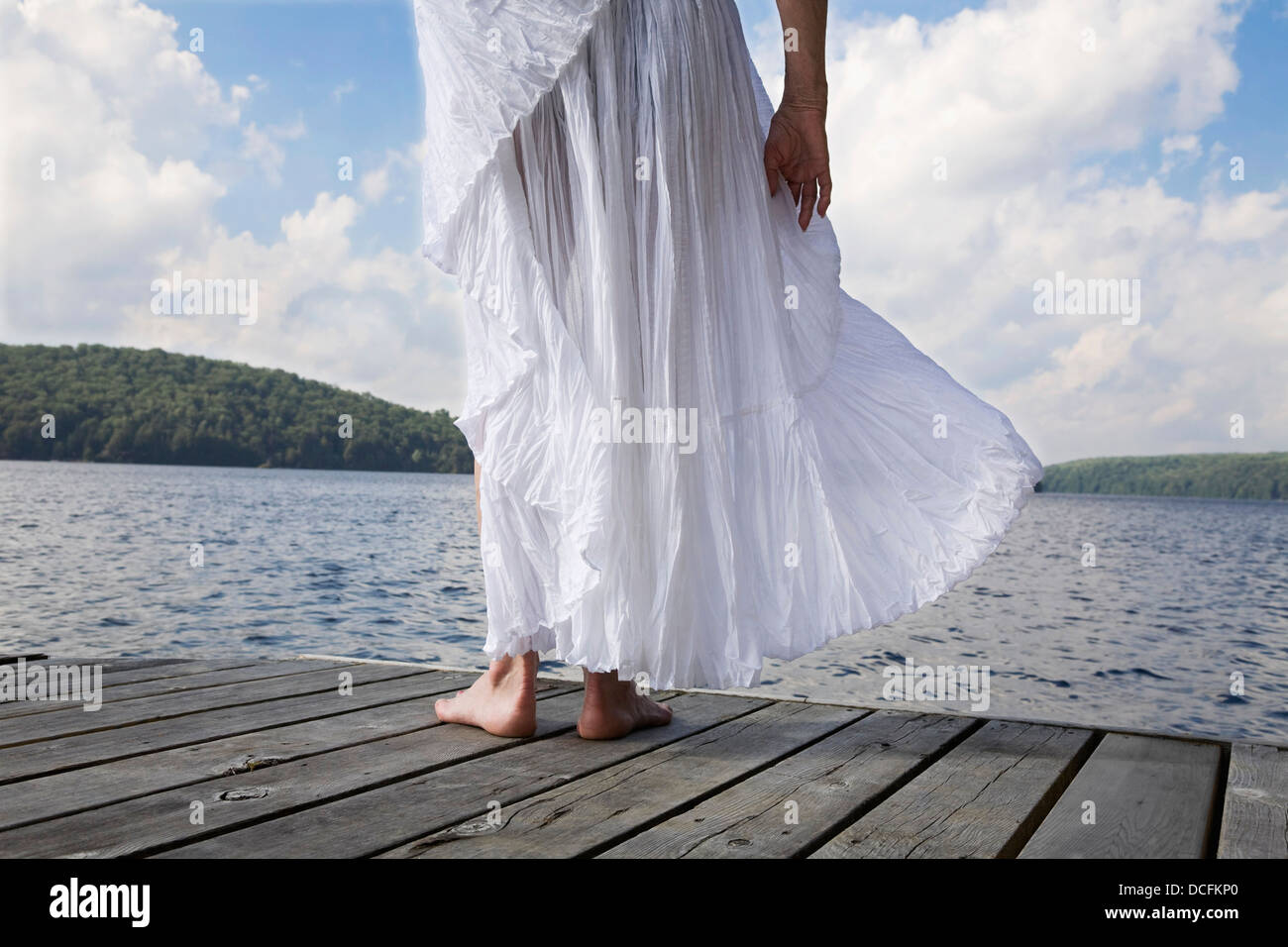 Woman On Cottage Dock With White Skirt Blowing In The Wind