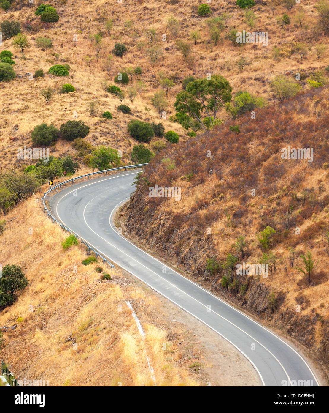 Winding tarred road in the countryside snaking through dry hilly terrain viewed from above Stock Photo