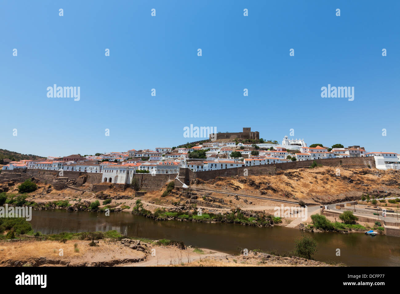 Walled fortified town on a hilltop protected by the ancient stone castle on the hill above which overlooks the town below Stock Photo