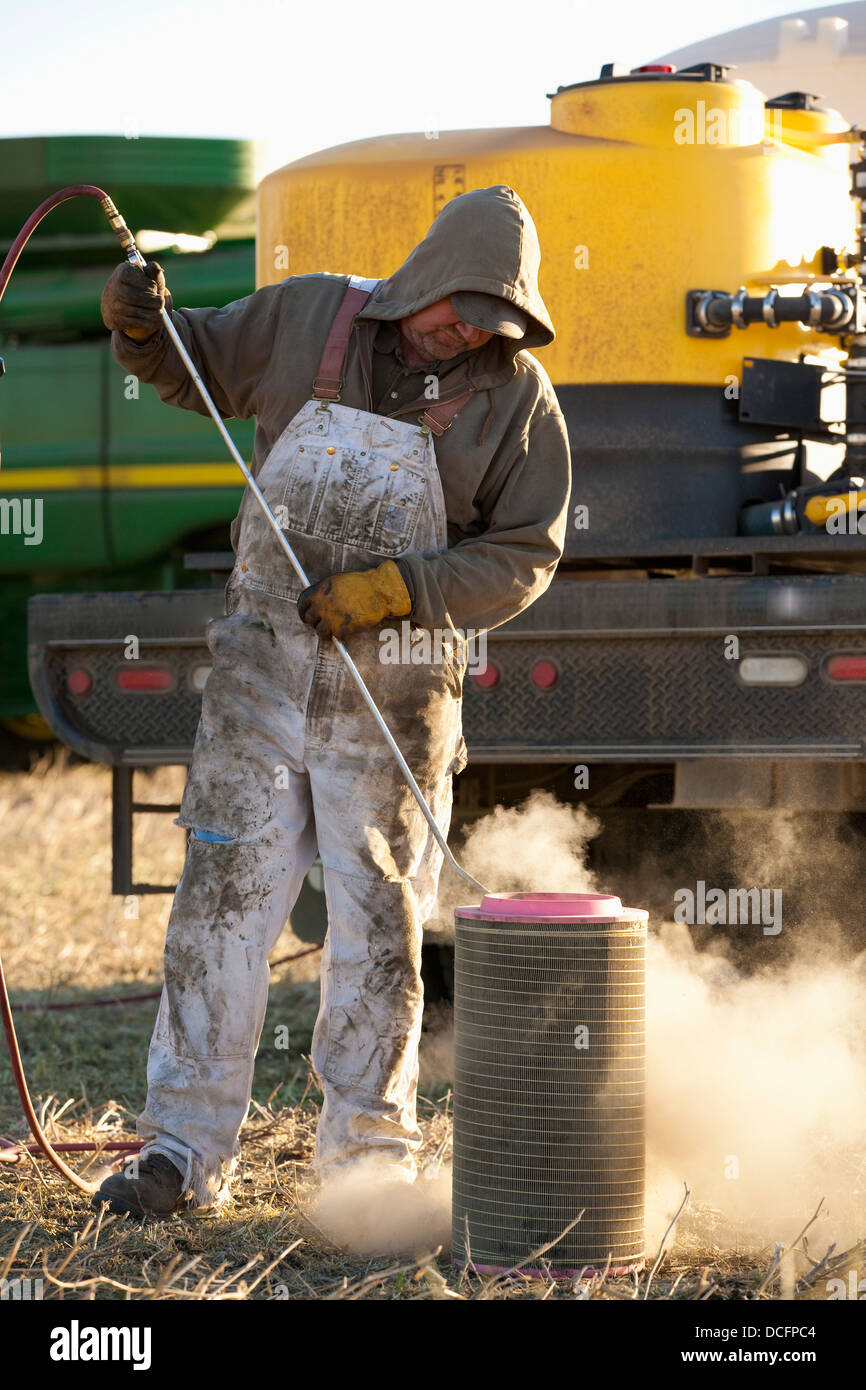 A Person Cleans A Filter For Farm Equipment; Three Hills, Alberta, Canada Stock Photo