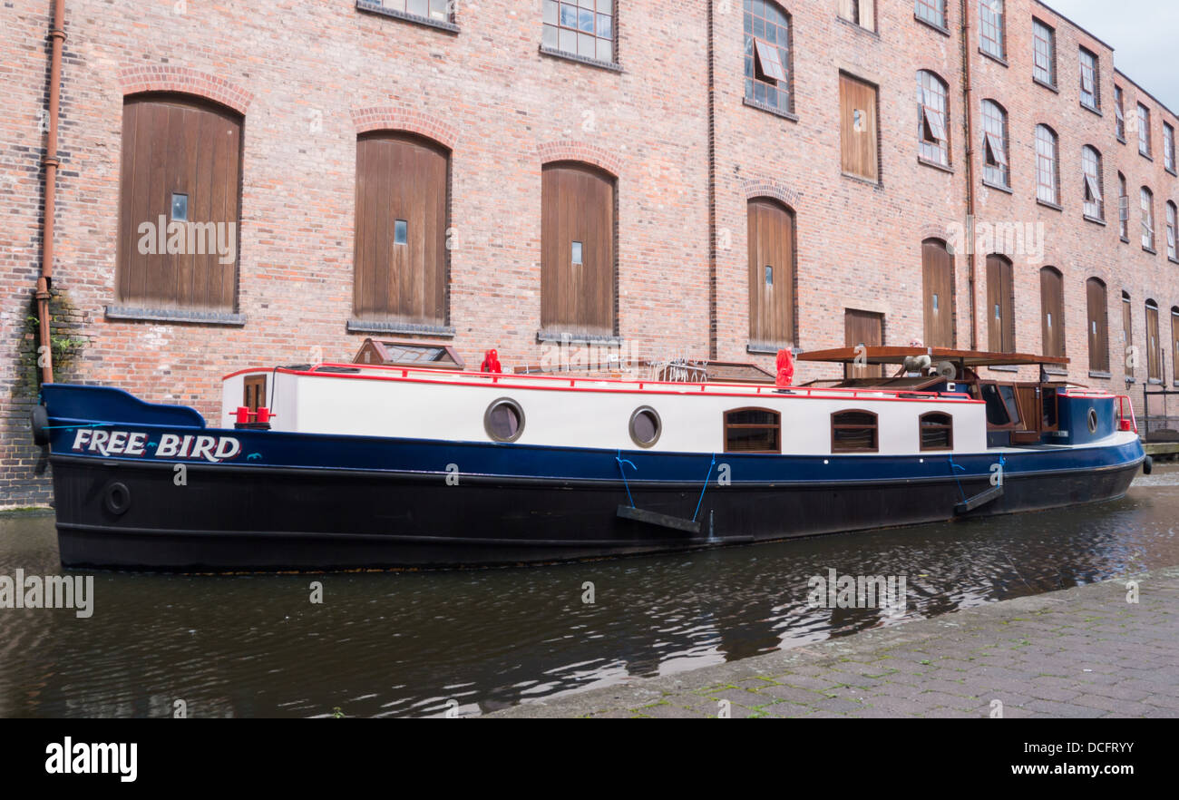 Canal boat sailing past an old red brick building on the Nottingham canal. Stock Photo