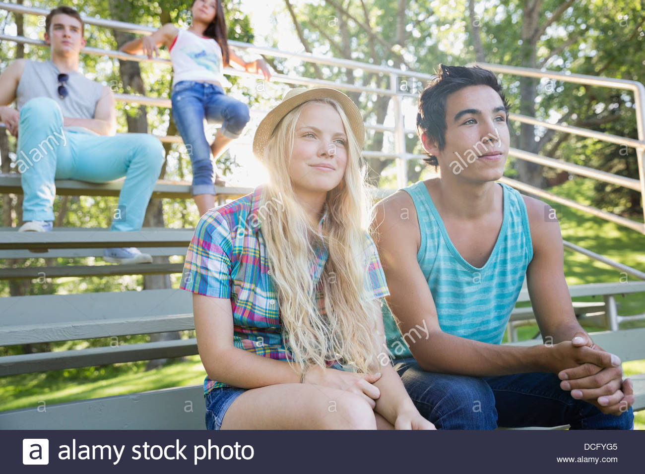 Teens sitting on park bleachers Stock Photo