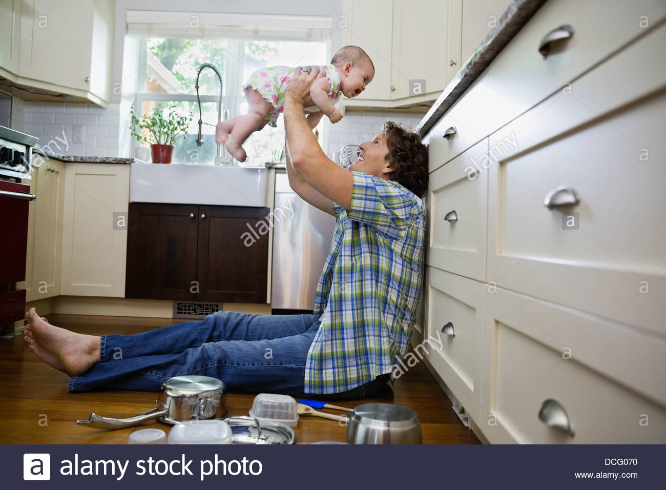 Profile shot of father playing with baby girl in kitchen Stock Photo