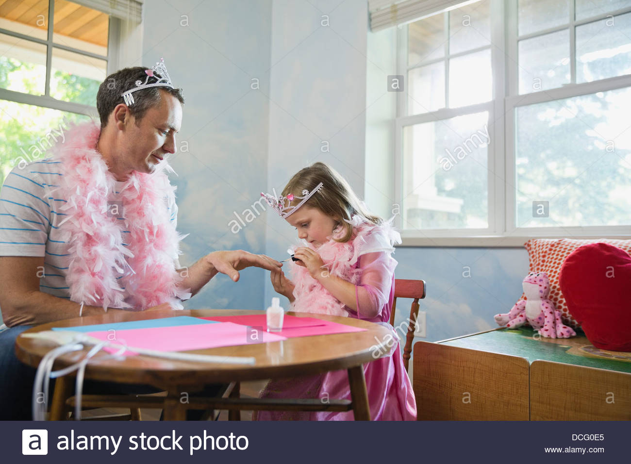 Little girl painting fathers fingernails at table Stock Photo