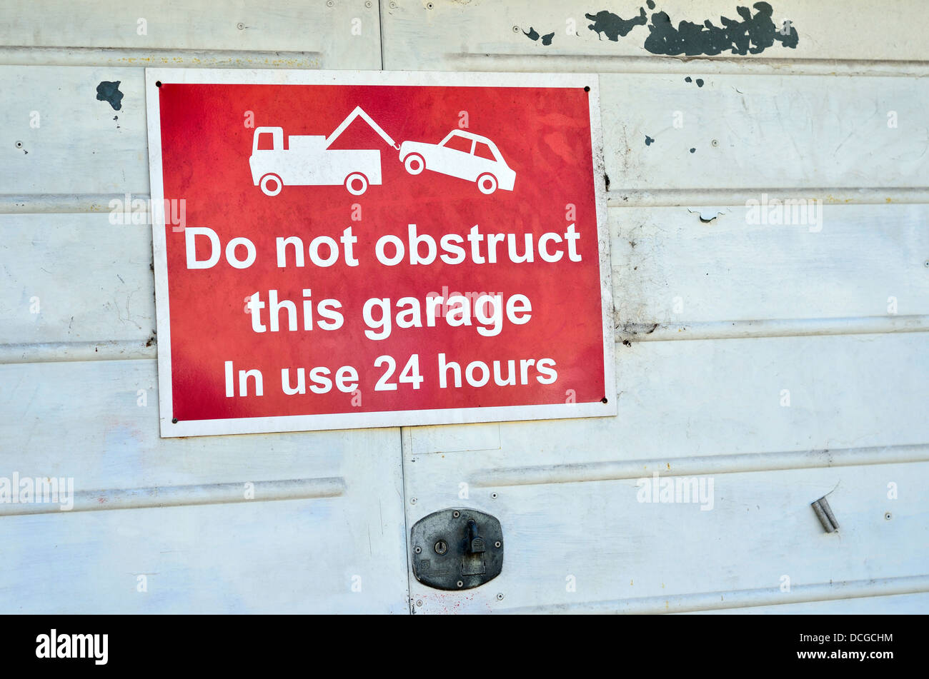 Red sign on white garage door 'Do not obstruct this garage' Stock Photo