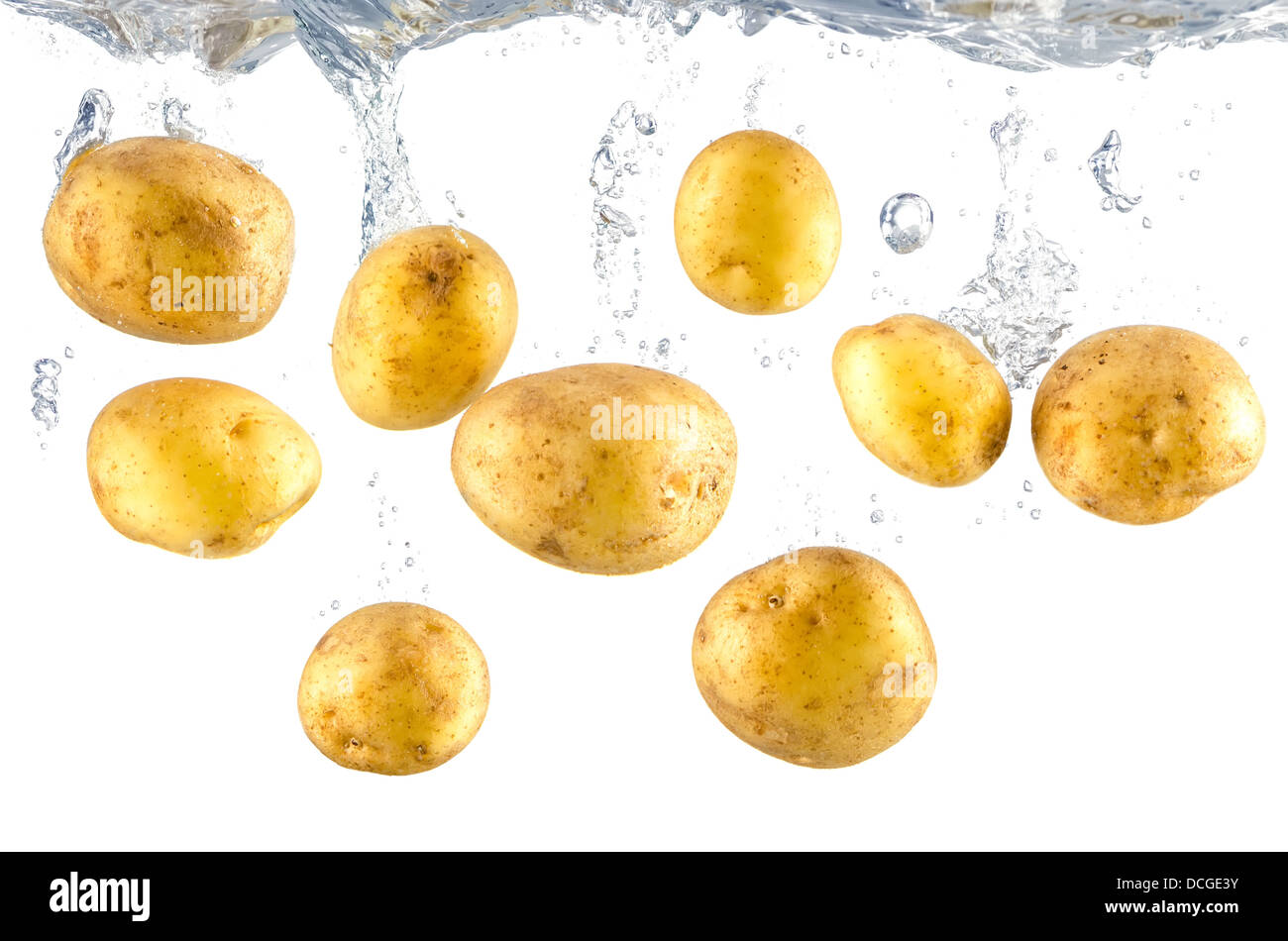 many raw potatoes fall into water before white background Stock Photo