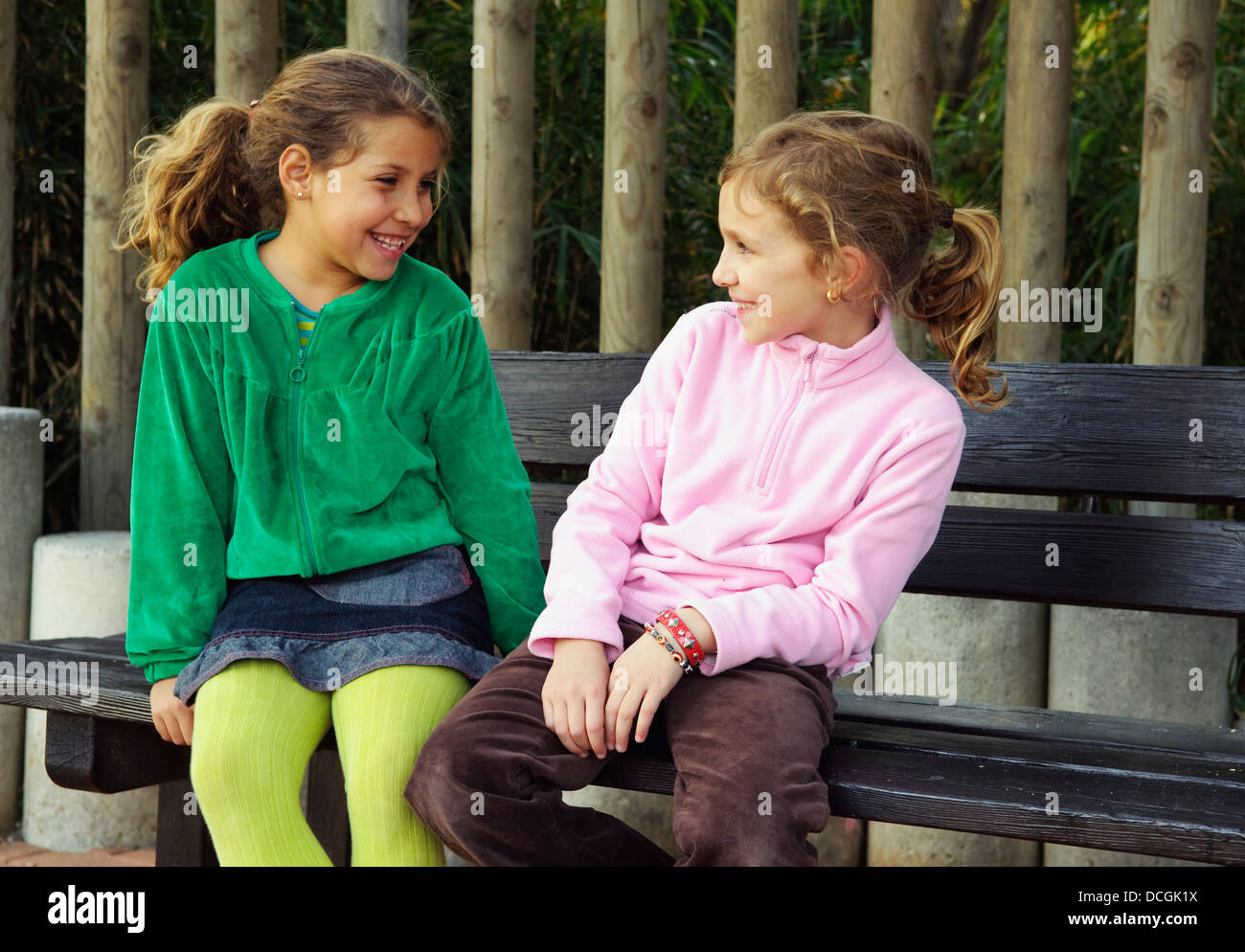 Two Girls Sitting Together Outdoors Stock Photo