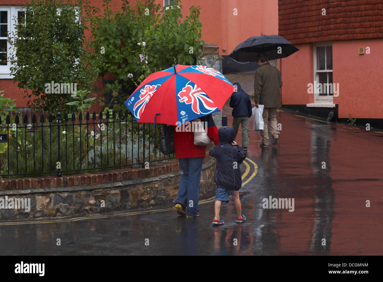 Lyme Regis, UK 17 August 2013. Tourists brave the wet weather.  Family walk along the streets under umbrellas trying to keep dry under the shelter. Credit:  Carolyn Jenkins/Alamy Live News Stock Photo