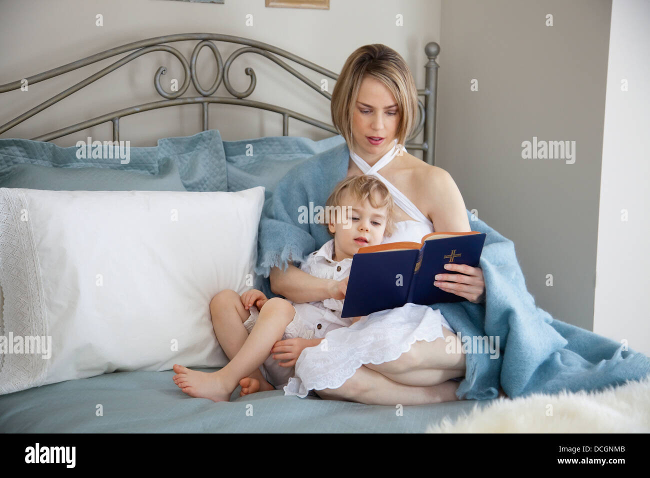 Toddler And Mother In Bed Reading; Jordan, Ontario, Canada Stock Photo