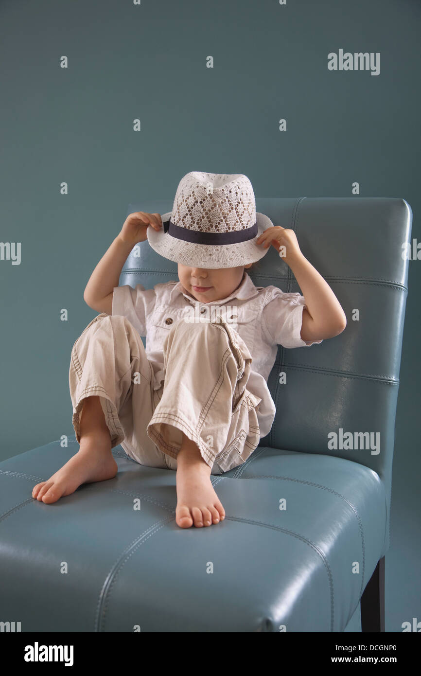 Toddler Sitting In A Big Chair Wearing A Hat; Jordan, Ontario, Canada Stock Photo