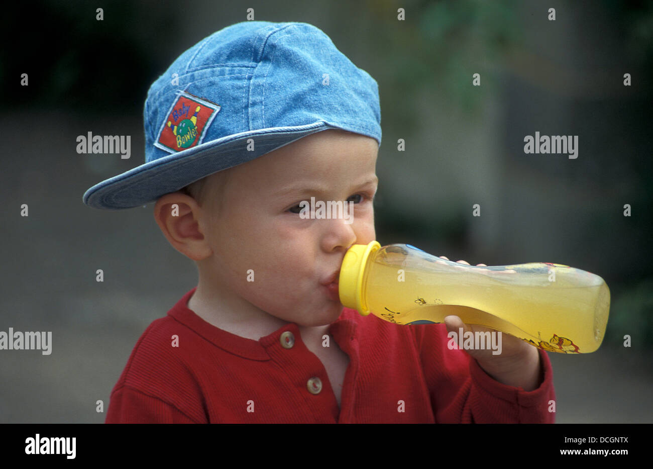 toddler drinking orange juice from gripper bottle Stock Photo