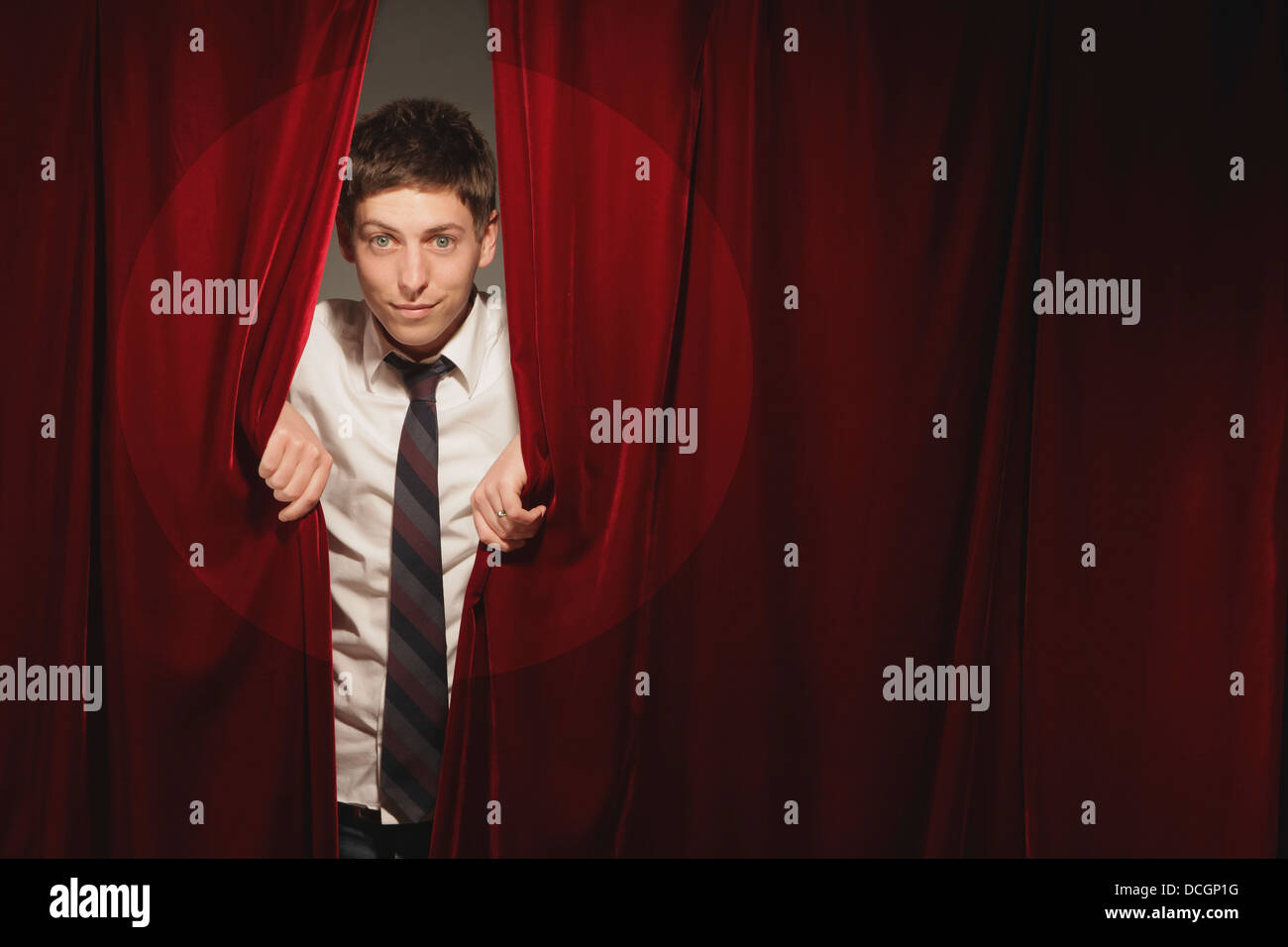 Man Peeking From Behind Red Stage Curtain Stock Photo